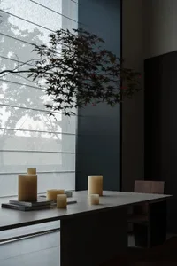 A minimalist dining room featuring wood textures and candlelight ambiance.