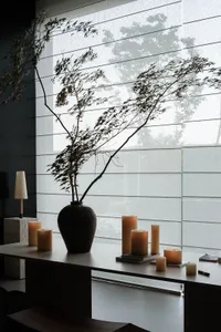 A minimalist interior space featuring a ceramic vase with a floral arrangement.