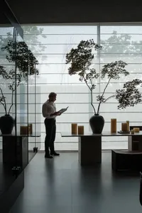 A minimalist room featuring transparent windows with plants and candles.