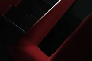 Black wooden stairs with red walls and a single light source.
