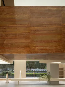 A modern interior with wooden paneling and glass windows showing a view of a road and greenery outside.