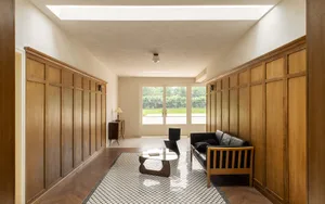 A modern lobby features wooden walls, glass walls, and a glass coffee table.