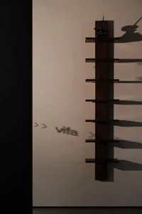 A modern wooden shelf mounted on a wall with shadows reflecting on it.