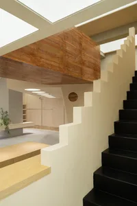 A modern staircase with concrete steps and a wooden handrail in a minimalist interior design setting.
