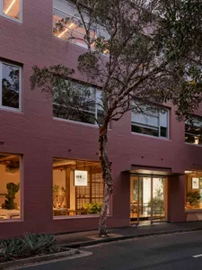 A modern retail shop with a pink brick exterior on a street corner.