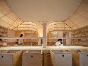 A modern library interior with wooden elements and light-colored fabric ceilings.