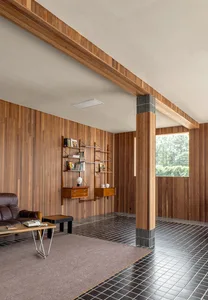 A modern living room with wooden walls, black and white tiled flooring, and a mix of furniture and decor items.