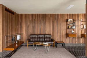 A modern living room featuring wooden paneling, a brown leather sofa, and a coffee table.