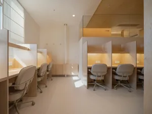 Minimalist private study cubicles with beige chairs and wood paneling.