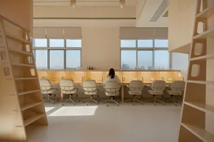 A spacious, industrial-style workspace featuring wooden furniture and a long desk with a view of the city.
