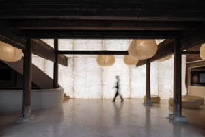 A spacious, industrial-style interior space with concrete floors and ambient lighting.