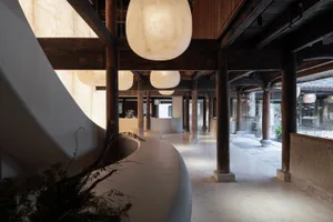 Wide-angle photograph of a sleek, contemporary hotel reception hall featuring concrete flooring, white walls, wooden beams, a