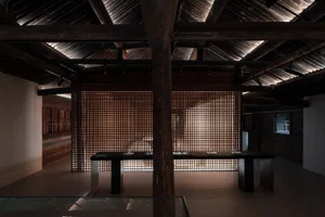 A traditional woven wall interior featuring wooden beams and a glass-topped table with items on it.