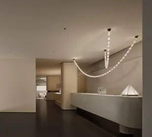 A modern commercial lobby featuring contemporary lighting fixtures, minimalist decor, and mixed materials.