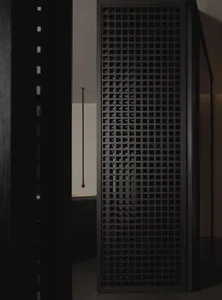A modern interior space featuring a black grid-patterned wooden door, creating a minimalist and sleek aesthetic.