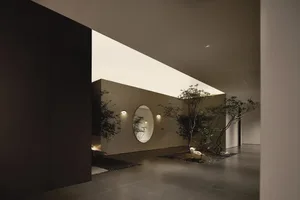 A modern interior hallway with concrete flooring, glass featured walls, and wooden joinery.