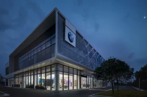 Modern office building with glass walls, concrete structure, and illuminated facade.