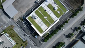 Aerial view of a modern building with a green rooftop and concrete exterior.