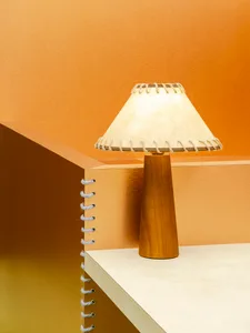 A contemporary lamp with a wooden base and textured paper shade.