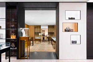 A luxurious retail shop featuring glass exhibit cases, wooden floors, and patterned carpet.