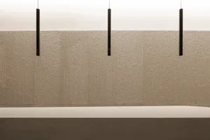 A minimalist interior space featuring a textured wall and sleek, modern lighting fixtures.