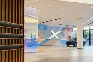 Modern auto dealership interior with colorful geometric wall and blue cars.