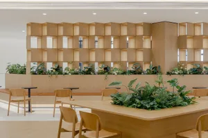A modern cafeteria with wooden furniture and vegetation.