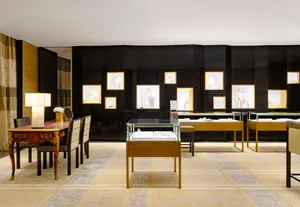 A modern jewelry store with glass cases displaying jewelry, wooden tables, and gold accents.