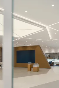 A modern lobby featuring a sleek, minimalist design with a wooden ceiling and a large screen.
