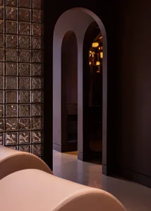 Glass block corridor with arched doorway, lit entryway, and modern interior design.