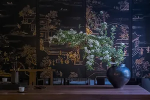 Decorative floral arrangement in a ceramic vase on a wooden table in an interior design setting.