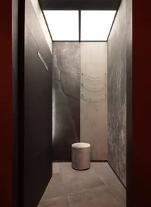 A minimalist fitting room with concrete walls and a modern, upholstered stool.