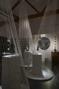 A contemporary museum exhibit featuring hanging fabric textile installations and sculptures.