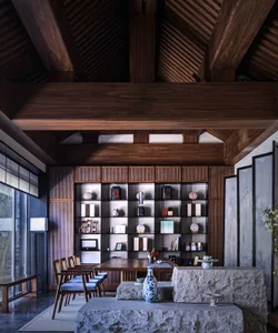 A modern living room featuring wooden furniture, stone elements, and glass windows.
