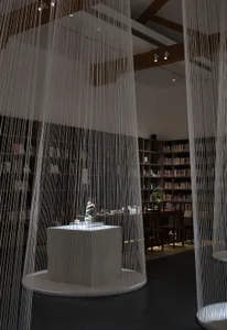 A modern library with concrete textured flooring and bookshelves lining the walls.