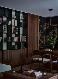 A modern living room featuring a black bookshelf with various books and decorative items, accompanied by wooden furniture and