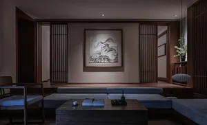 A modern minimalist living room featuring wooden furniture, a black coffee table, a grey sectional sofa, and a framed black a