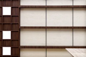 Modern, minimalist bookshelf with wooden shelves against a textured wall background.