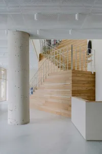 Modern office space featuring wooden stairs and a concrete pillar