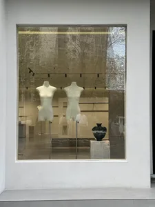 Modern interior design storefront window display featuring glass mannequins and a vase.
