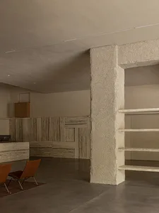 A modern, minimalist living room with concrete walls and floors, featuring a sleek, minimalist sofa and a simple, functional 