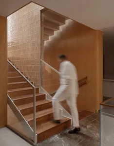 A modern wooden staircase with a glass wall and polished marble floor.