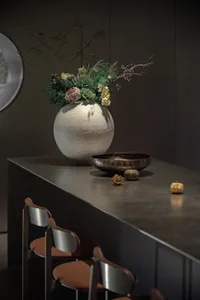 A modern interior decorative arrangement featuring a ceramic vase with a plant bowl and decorative pumpkins.