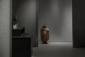 A minimalist lobby with metal furniture and a small lantern on the floor.