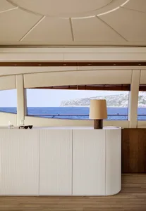 A residential living room with a wood cabinet, a table lamp, and a view of the ocean.
