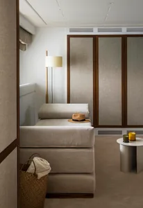 A minimalist bedroom with fabric elements, featuring a bed, floor lamp, and storage basket.