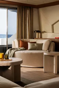 Modern living room with a neutral color palette, featuring a round sofa, round side tables, and a large window overlooking th