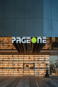 The exterior of a bookstore with a large, illuminated storefront featuring a modern design with light wood and glass elements