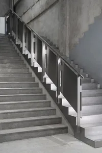 Staircase with industrial design, featuring metal railings and concrete steps on a concrete floor.