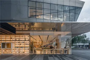A modern coffee shop with large glass windows and a wooden interior, featuring a bar area with stools and a small table.